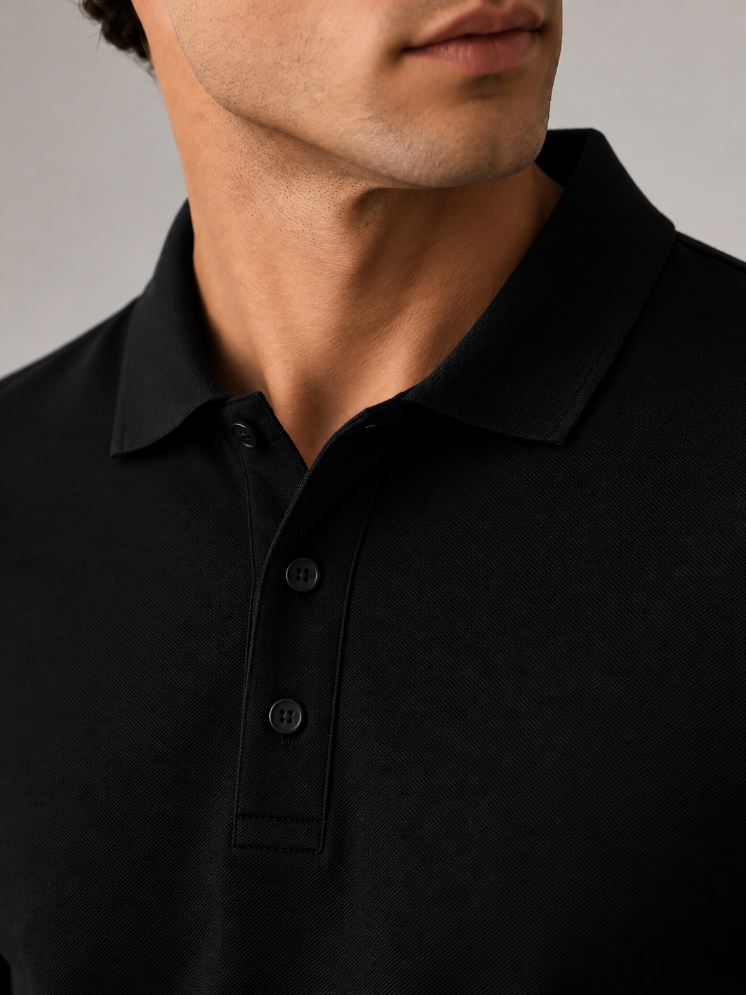 Men’s black minimalist polo shirt, flat lay front view, crisp spread collar and tonal buttons